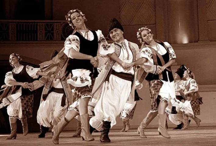 Costumed folk dancers performing a lively partner dance on stage
