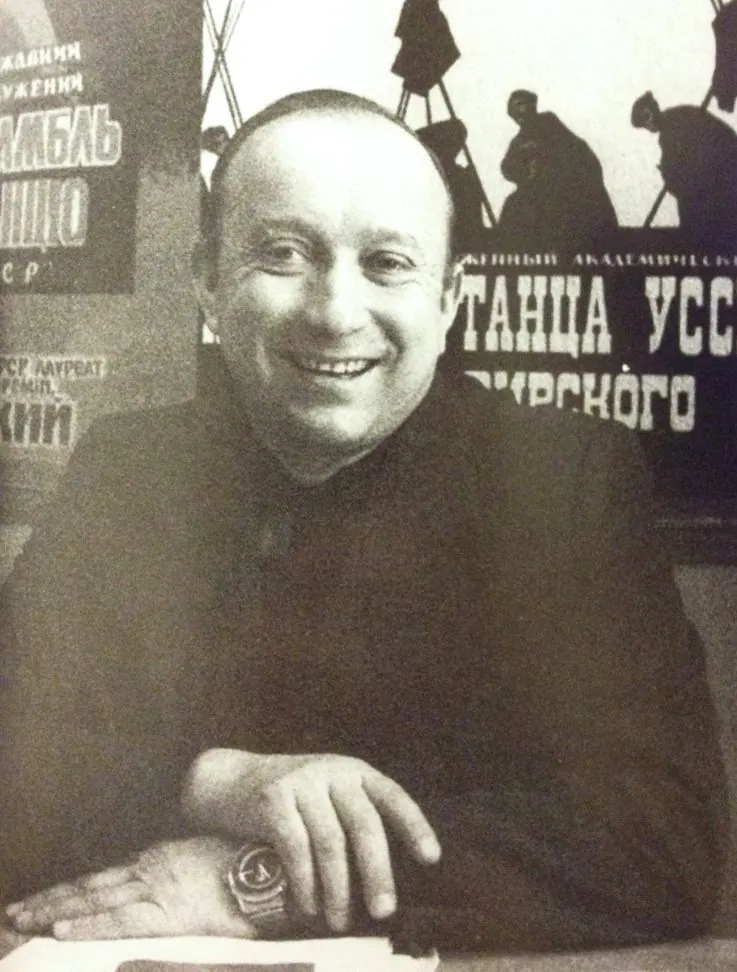 An archival portrait of Myroslav Vantukh seated in front of a Virsky Ensemble poster