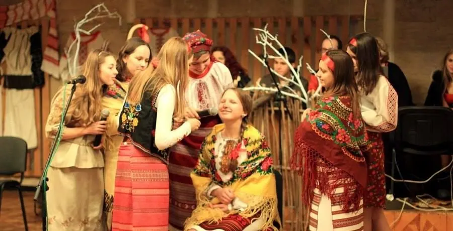 A group of young Ukrainian singers and dancers in traditional costume sharing a warm moment together backstage