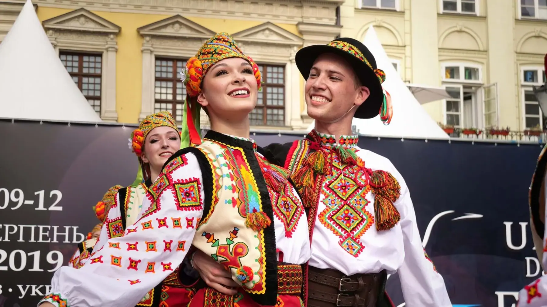 Dancers in traditional Ukrainian costume smiling at a festival
